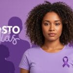 Uma mulher brasileira de pele morena clara, expressão firme e serena, usando camiseta lilás em um fundo com tons suaves da mesma cor. Ao fundo, silhuetas simbólicas de outras mulheres unidas, representando sororidade. O cenário transmite esperança e força. Elementos visuais sutis indicam proteção, como luz suave em torno da personagem principal. O estilo é realista e levemente editorial, próprio para capa de artigo informativo sobre violência contra a mulher no contexto do Agosto Lilás.